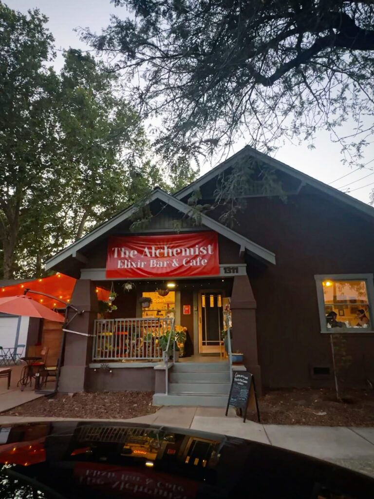 Exterior entrance of Alchemist Café & Elixir Bar in downtown Modesto at dusk.