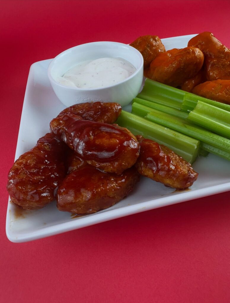 Close-up of MorningStar Farms BBQ Chik'n Wings with vegan ranch and celery sticks on a serving platter.