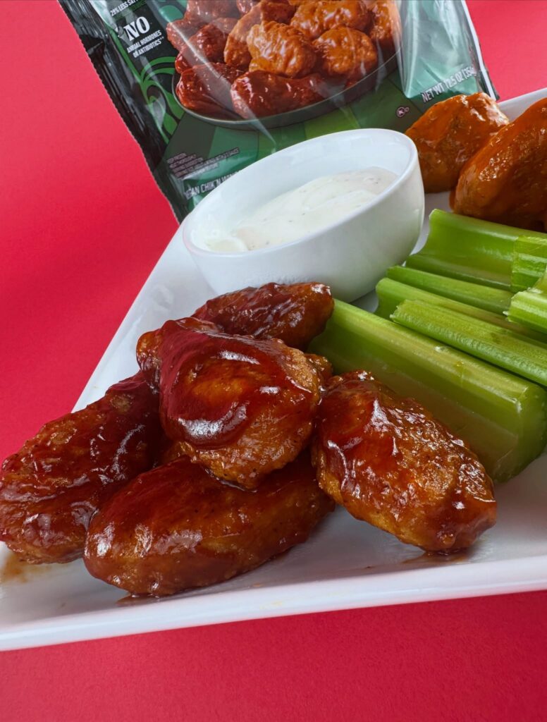Close-up of MorningStar Farms BBQ Chik'n Wings with vegan ranch, celery sticks, and Buffalo wings in the background.