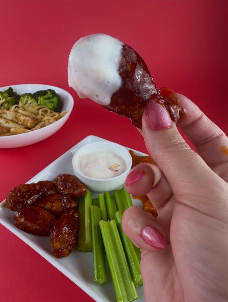 Hand dipping a MorningStar Farms BBQ Chik'n Wing into vegan ranch dressing.