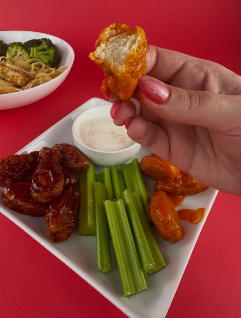 Hand holding a bitten MorningStar Farms Buffalo Chik'n Wing showing the plant-based interior.