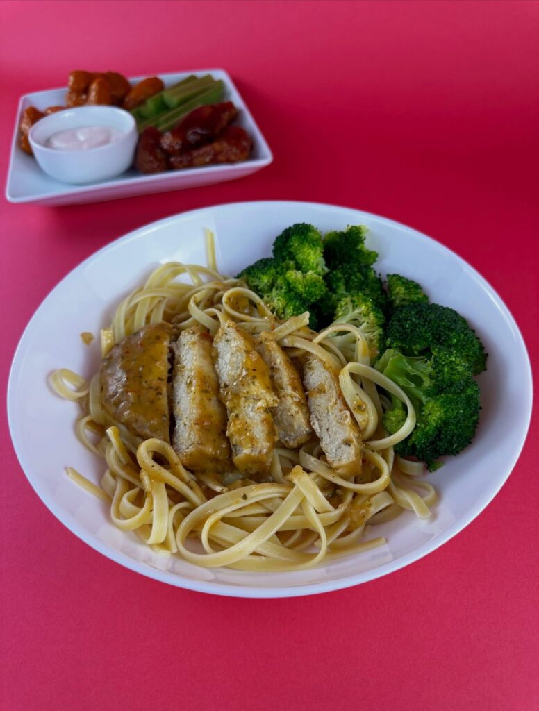 Sliced MorningStar Farms Chik'n Breast over linguine pasta with steamed broccoli on a white bowl.