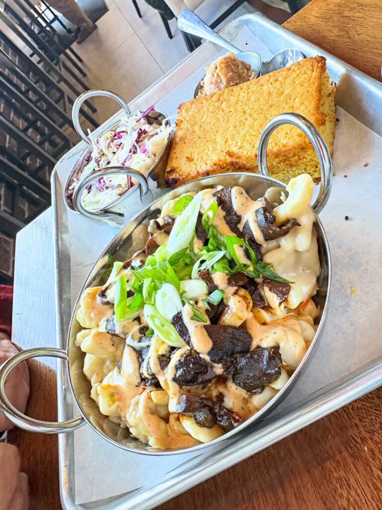 Fungi Foods BBQ Cajun Mac topped with BBQ maitake mushrooms and scallions, served with coleslaw and cornbread.