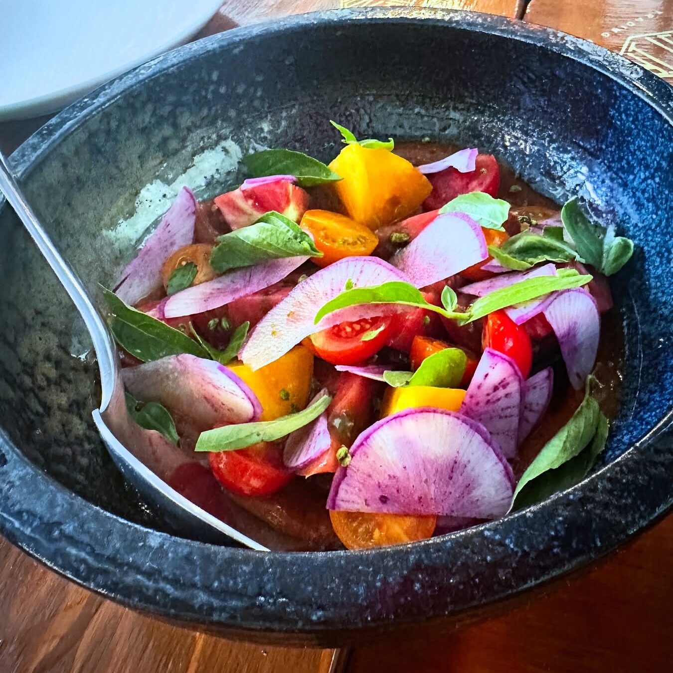 Heirloom tomato salad with peach chamoy, shaved purple daikon, cherry tomatoes, and fresh basil served during Vegan Roast.