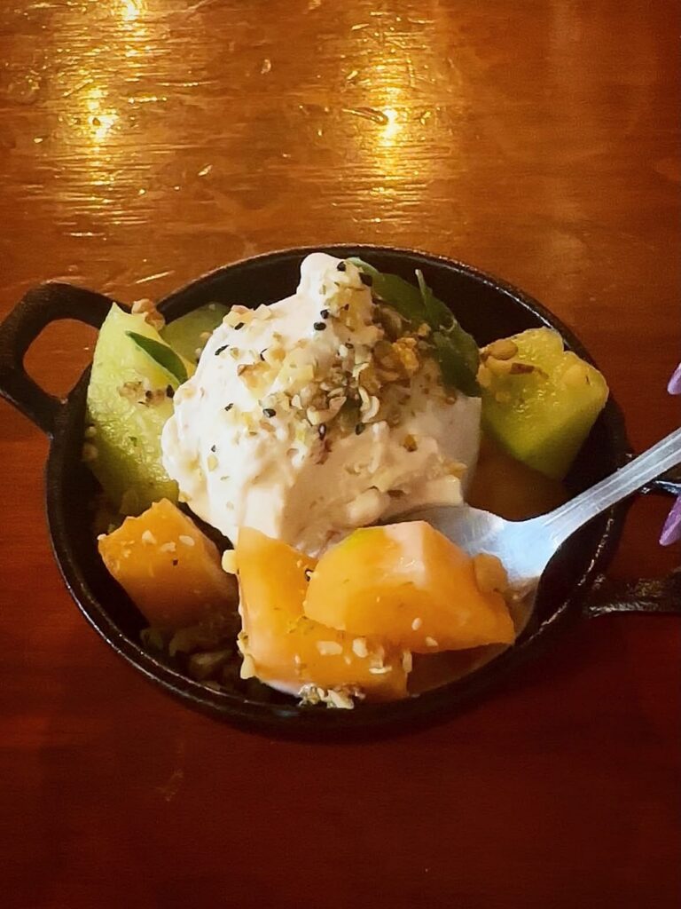 bite shot of Fresh melon served with oat ice cream, seeded brittle, basil, and rosemary oil for dessert at Vegan Roast.