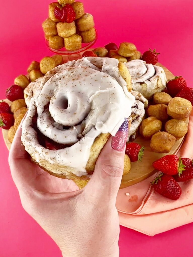 Close-up of a cut vegan gluten-free cinnamon roll showing its cinnamon filling and iced layers.