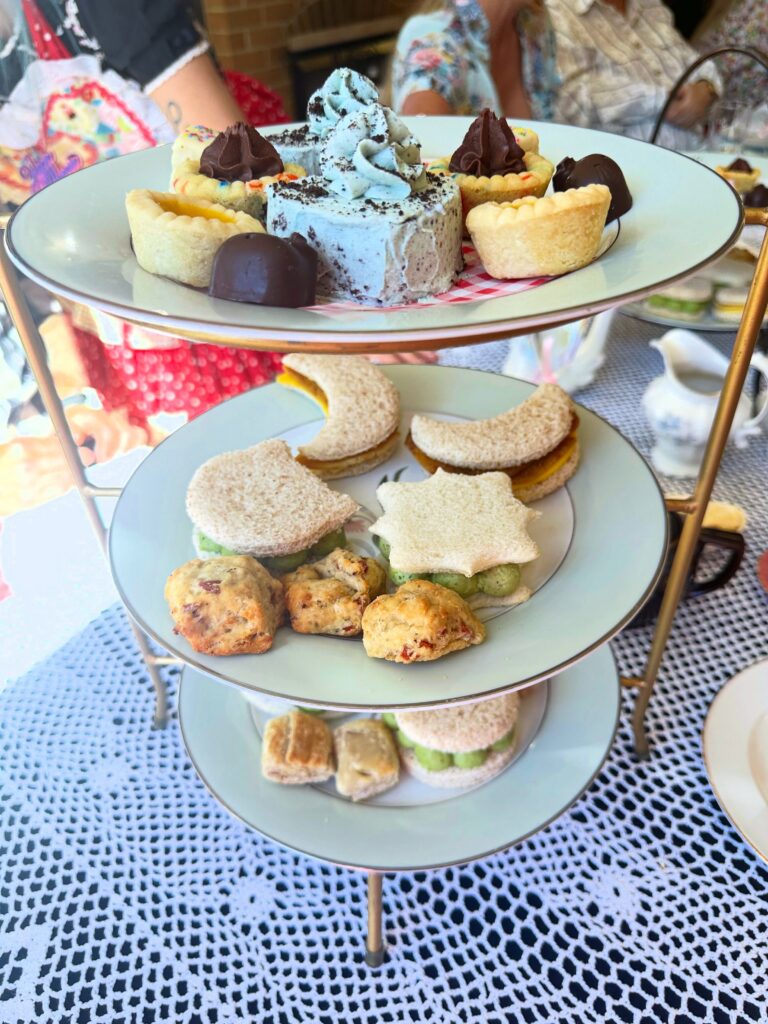 Close-up of the Vegan Dollhouse afternoon tea stand with vegan desserts, finger sandwiches, pizza biscuits, and sausage rolls.