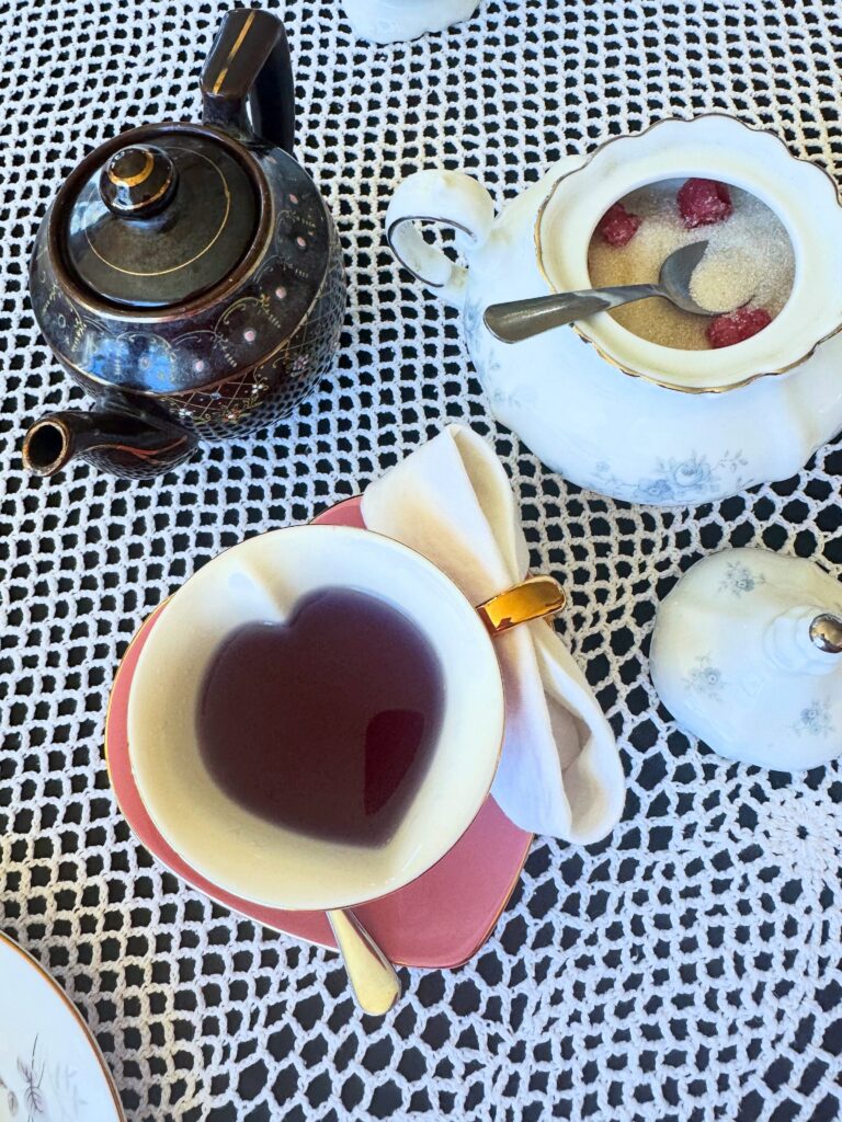 Purple herbal tea served in a pink heart-shaped teacup beside a floral teapot at Lady Bird Tea House.