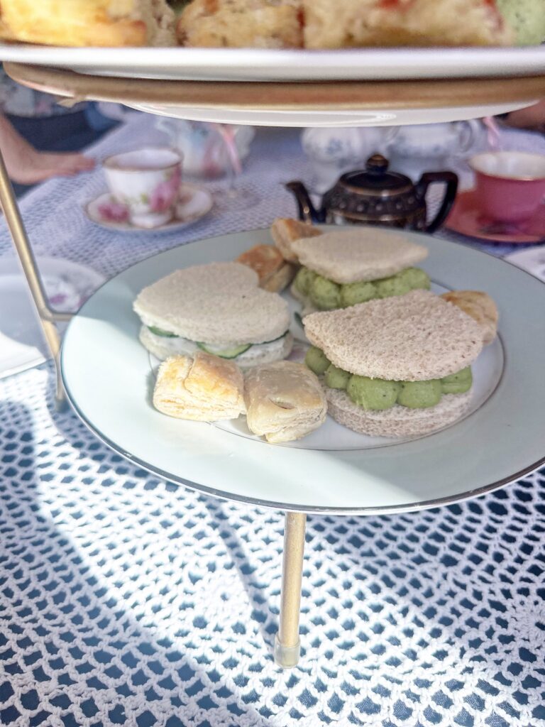 Assorted vegan finger sandwiches arranged on the middle tier of an afternoon tea stand.