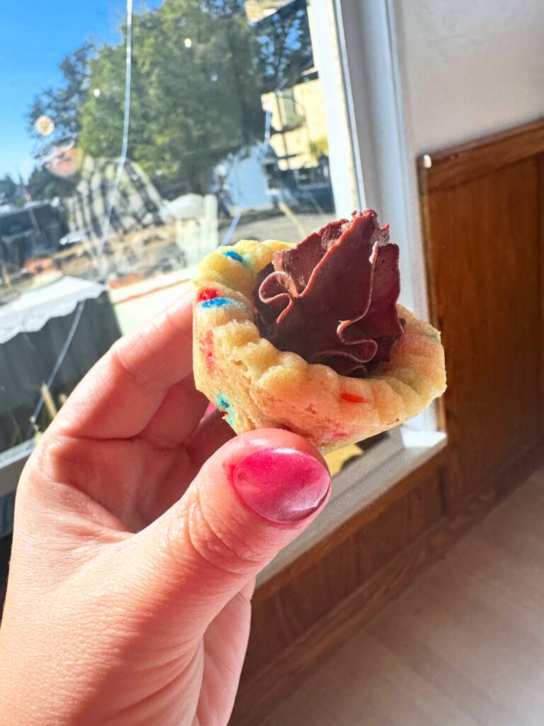 Vegan confetti cookie cup filled with chocolate mousse and held in front of a window.