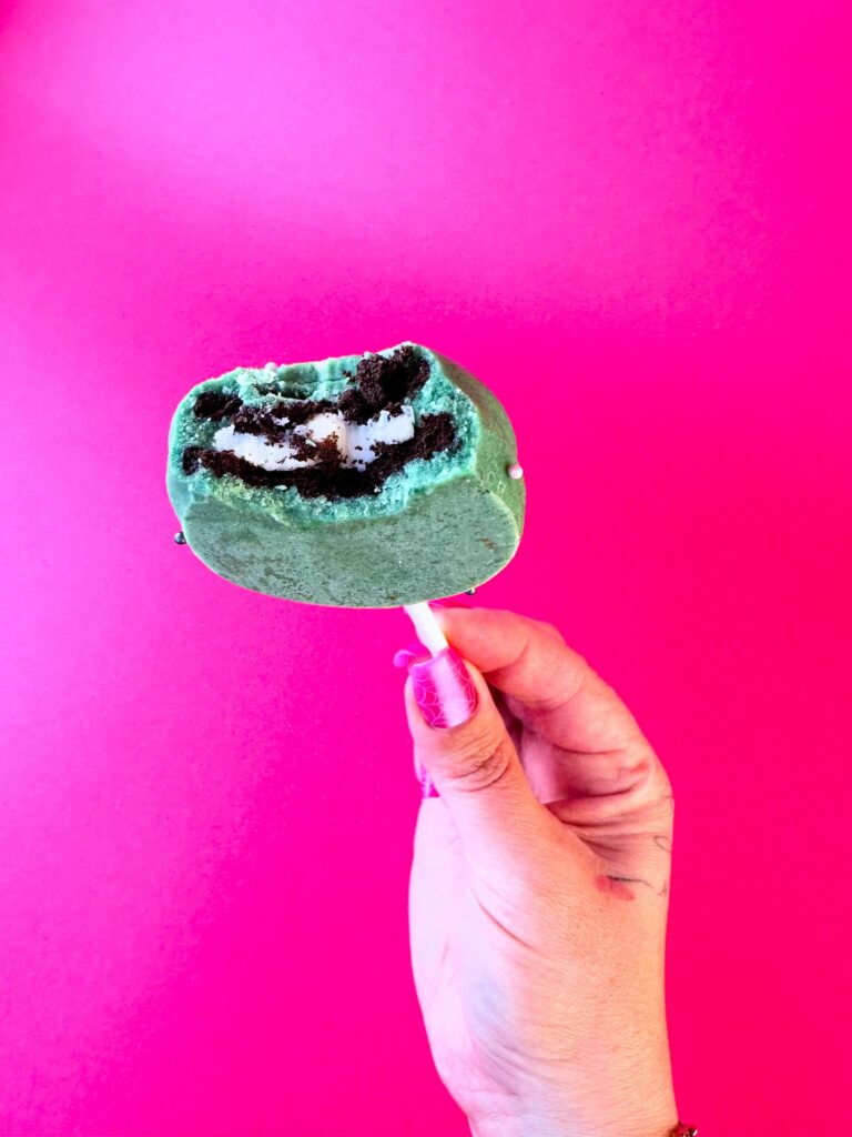 Inside of a Vegan Dollhouse Green Monster Cookie Pop showing chocolate covered sandwich cookie.